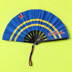 Flat lay of Aruba flag inspired bamboo folding hand fan along with black suede satchel bag with Caribae Kiss white logo print.
