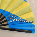 Close up of Bahamas flag inspired bamboo folding hand fan displaying the country's name in script font and displaying the Caribae Kiss logo.
