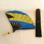 Bahamas flag inspired bamboo folding hand fan halfway open along with black suede satchel bag with Caribae Kiss white logo print.