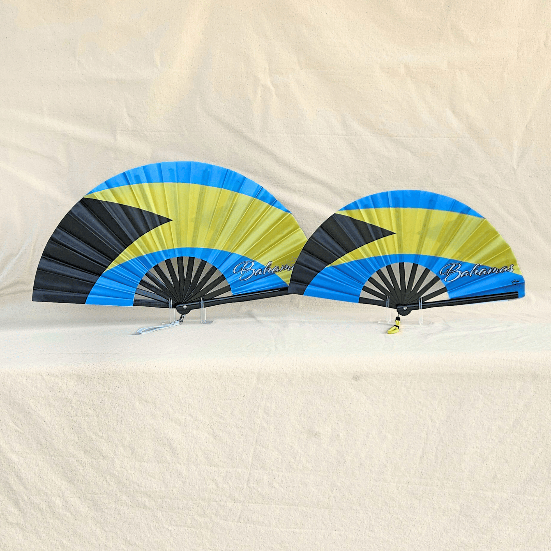 Bahamas flag inspired bamboo folding hand fans of various sizes (large and small) open and standing.