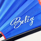 Close up of Belize flag inspired bamboo folding hand fan displaying the country's name in script font and displaying the Caribae Kiss logo.
