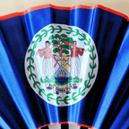 Close up of Belize flag inspired bamboo folding hand fan.  Close up of the national emblem image. Sub Umbra Flor Eo
