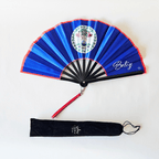 Flat lay of Belize flag inspired bamboo folding hand fan along with black suede satchel bag with Caribae Kiss white logo print.
