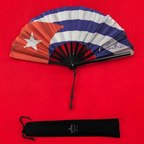 Flat lay of Cuba flag inspired bamboo folding hand fan along with black suede satchel bag with Caribae Kiss white logo print.
