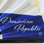 Close up of Dominican Republic flag inspired bamboo folding hand fan displaying the country's name in script font and displaying the Caribae Kiss logo.