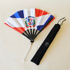 Dominican Republic flag inspired bamboo folding hand fan halfway open along with black suede satchel bag with Caribae Kiss white logo print.
