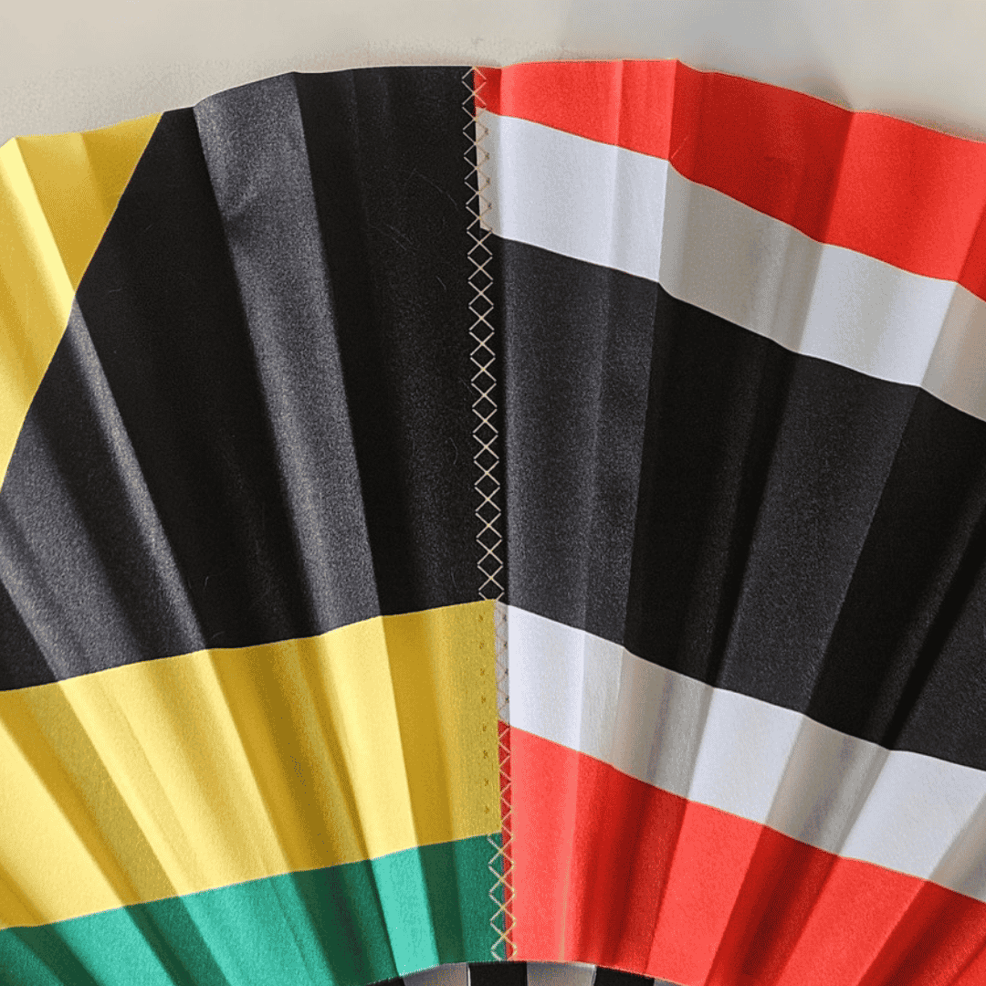 Close up of Dual Heritage Jamaica and Trinidad & Tobago flag inspired bamboo folding hand fan displaying the graft line design that represents two cultures merging into one.