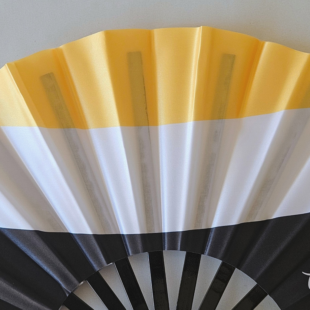 Close up of Garifuna flag inspired bamboo folding hand fan.  Close up of flags colors of yellow white and black.