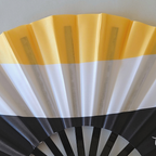 Close up of Garifuna flag inspired bamboo folding hand fan.  Close up of flags colors of yellow white and black.