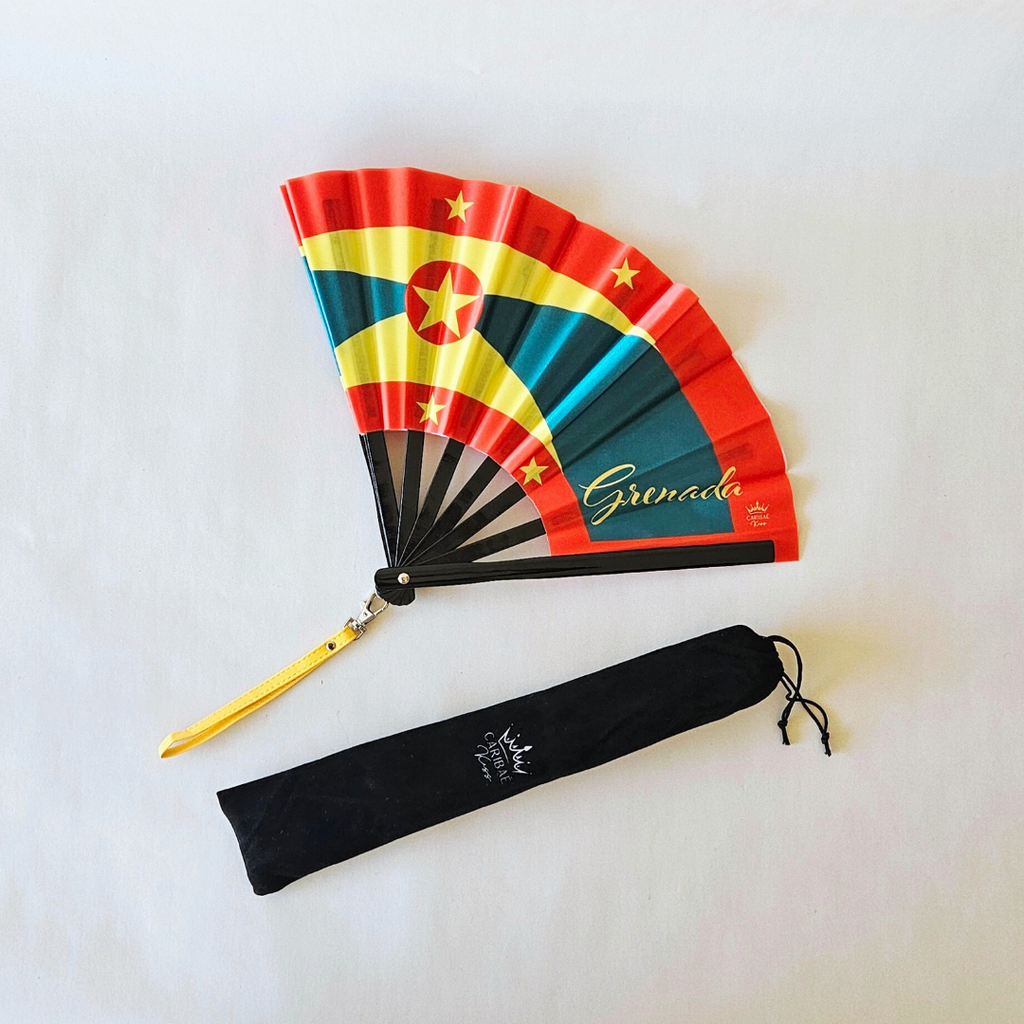 Grenada flag inspired bamboo folding hand fan halfway open along with black suede satchel bag with Caribae Kiss white logo print.