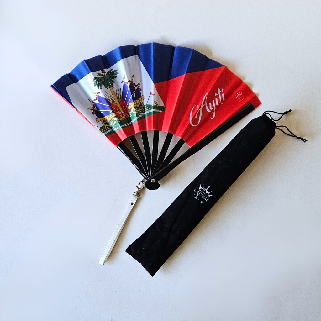 Haiti "Ayiti" flag inspired bamboo folding hand fan halfway open along with black suede satchel bag with Caribae Kiss white logo print.