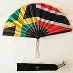 Flat lay of Jamaica and Trinidad & Tobago flag inspired dual heritage bamboo folding hand fan along with black suede satchel bag with Caribae Kiss white logo print.